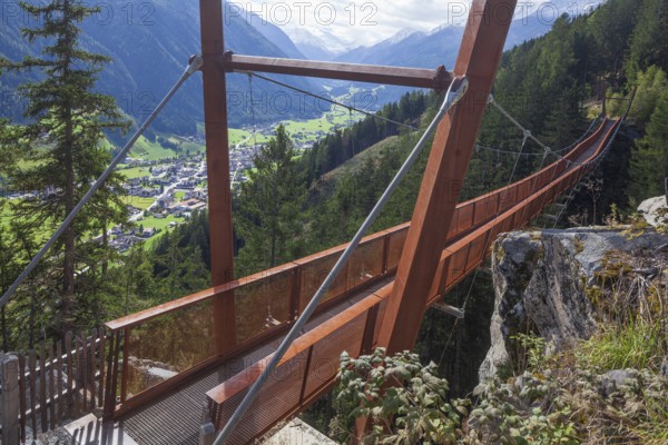 View of Neustift and Stubai Glacier from suspension bridge on the Sunnenseit'n-Weg hiking trail in autumn, Neustift im Stubai Valley, Stubai Valley, Tyrol, Austria