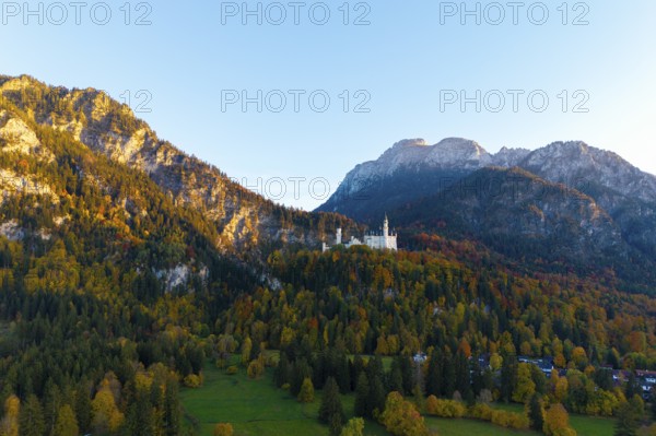 Neuschwanstein Castle perched on a wooded mountain in autumn light with a wide view of the valley, Schwangau near Füssen, Allgäu, Swabia, Bavaria, Germany