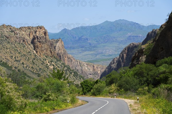 Road curves through a wide valley with mountain ranges in the background, picturesque road leading through the Amaghu Gorge from Noravank Monastery, Noravank, Vayots Dzor Province, Vayots Dzor, Armenia, Caucasus