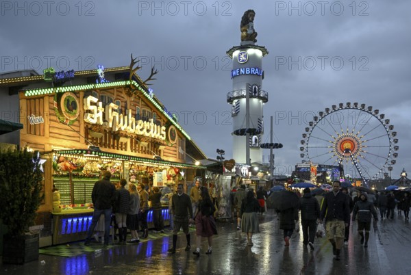 Oktoberfest visitors with umbrellas, rainy meadows, Löwenbräuturm, Ferris wheel, Munich, Bavaria, Germany