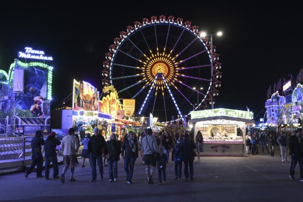 Oktoberfest visitors at night with the Ferris wheel in the background, Munich, Bavaria, Germany