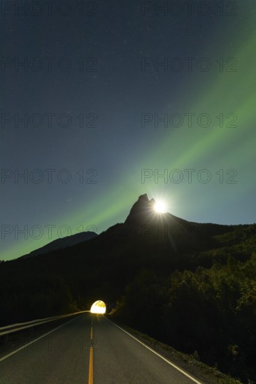 National mountain of Norway, Stetind in the Nordland under auroras and a full moon behind the summit. Entrance to the tunnel below the mountain