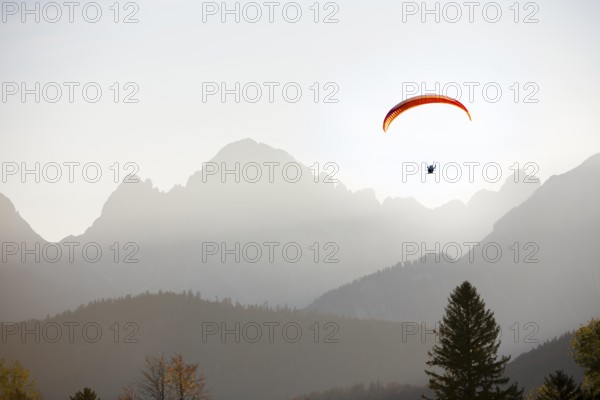 Paraglider at sunset over mountains surrounded by a peaceful atmosphere, Schwangau, Ostallgäu, Allgäu, Swabia, Bavaria, Germany