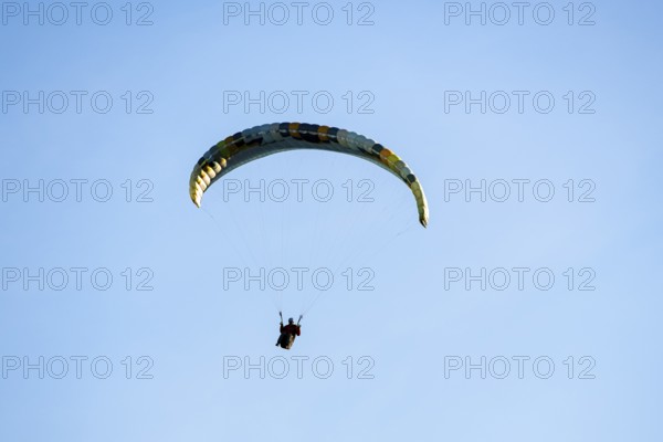 A single paraglider in front of a simple and minimalistic blue sky, Schwangau, Ostallgäu, Swabia, Bavaria, Germany