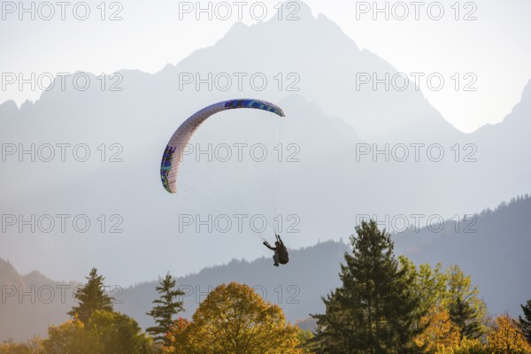 Paraglider floats against picturesque mountain scenery in autumnal weather and sunshine, Schwangau, Ostallgäu, Swabia, Bavaria, Germany
