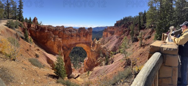Visitors look at a majestic rock arch from a vantage point in the canyon, Bryce Canyon National Park is located in southwestern Utah in the United States, tourists photograph a large rock arch in nature, Tropic, Utah, USA