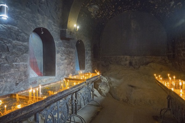 The room with candlelight creates a quiet, subdued atmosphere with stone walls, Khor Virap monastery, deep dungeon, Ararat province, Armenia