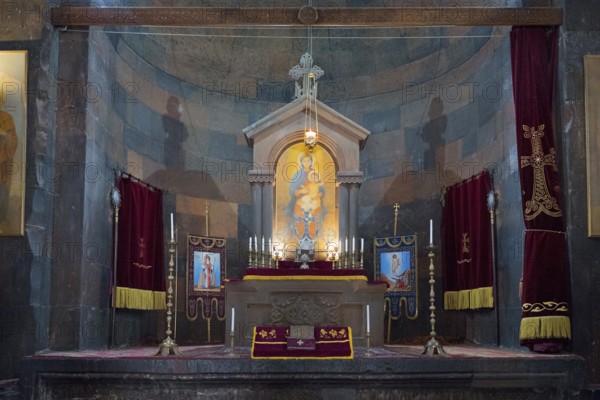 The altar stands in the church with religious icons, candles and deep shades of red, Khor Virap monastery, deep dungeon, Ararat province, Armenia