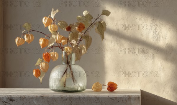 A vase of flowers sits on a table, with a few leaves scattered around it. The vase is filled with orange flowers, and the leaves are yellow. AI generated
