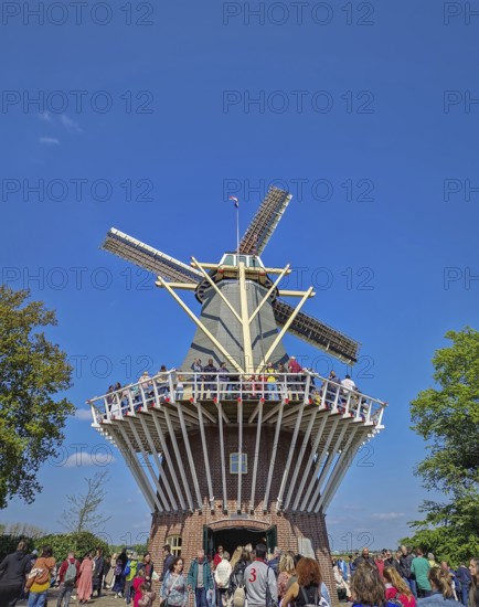 Lisse, Holland, Netherlands, April 25, 2025: the iconic brick windmill at Keukenhof, set against a clear blue sky and a large crowd of tourists gathering. Popular Dutch tourism landmark, Lisse, Holland, Netherlands