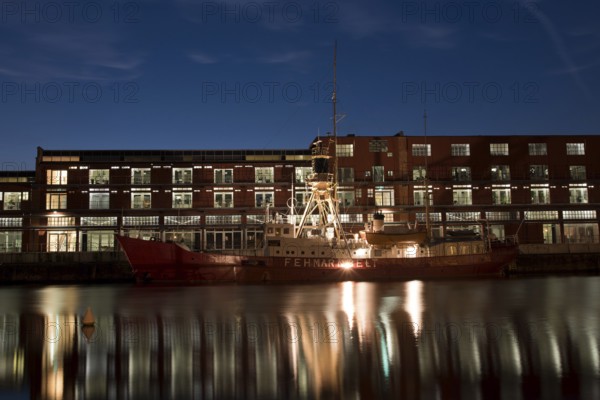 LUBECK, GERMANY - AUGUST 3, 2016: Ship in harbor during twilight. Lubeck is the 2nd largest city in Schleswig-Holstein region. Its old town is on a UNESCO World Heritage Site