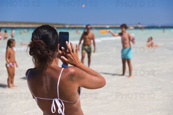STINTINO, ITALY - AUGUST 21, 2017 - Unidentified woman take picture people on the famous La Pelosa Beach on island Sardinia