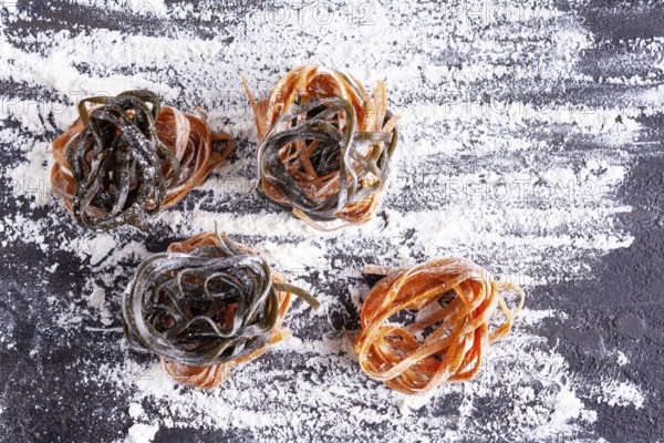 Pasta with carrots and spinach on a floured table, space for text