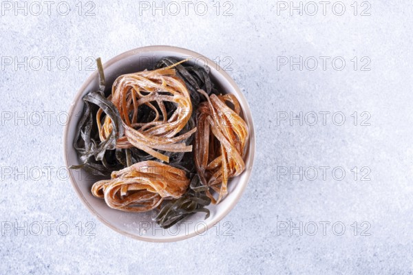Pasta with carrots and spinach in a round plate on a light textured background, top view, space for text