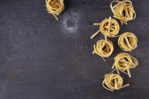 Tagliatelle on a dark textured background, top view, space for text