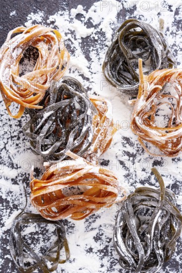Pasta with carrots and spinach on a floured table, space for text