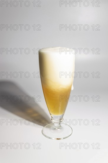 A drop of beer flows down a glass on a white background, copy space