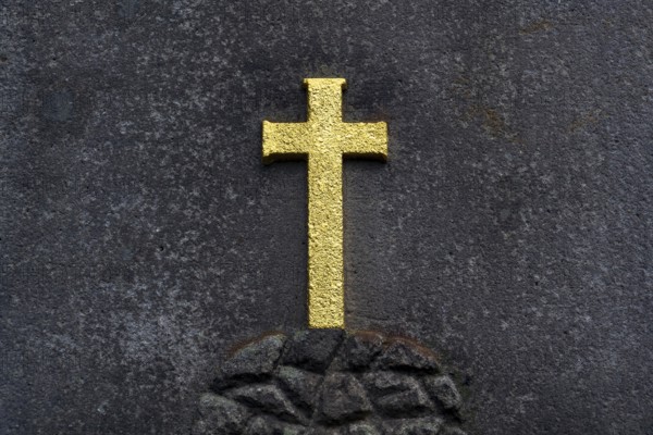 Golden Christian cross on stone background, tomb in the cemetery, life and death concept