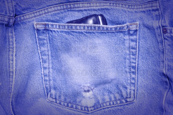 A Worn and tattered blue Jeans pocket. Carrying a wallet in your back pocket can hurt your back
