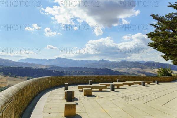 Ronda, malaga, spain viewpoint terrace offers stone benches for relaxing while observing the scenic mountain landscape under a bright sky in ronda, malaga, spain