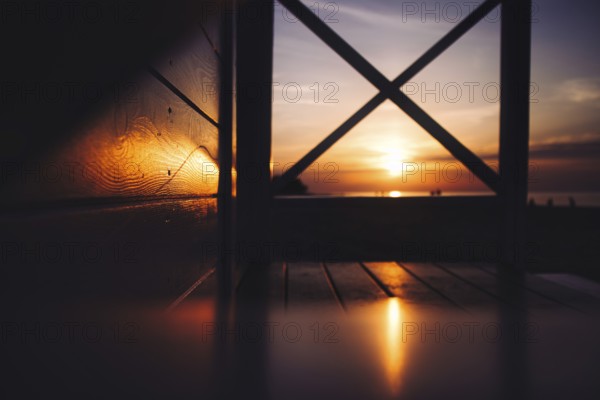 A warm sunset over the sea viewed through a wooden structure with visible reflections. Sea, Baltic, Poland, Kolobrzeg