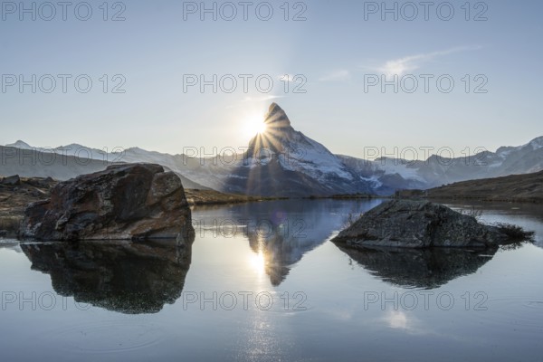 Matterhorn Mountain and Reflection in Lake Stellisee at Sunset. Sun is Setting behind the Mountain. Swiss Alps. Valais, Switzerland