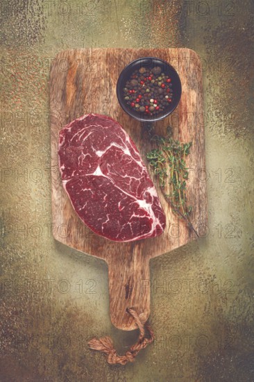 Steak made from fresh beef, with herbs and various spices, on a wooden chopping board, ready to cook, no people