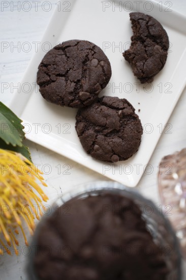 Chocolate chip cookies on a white plate with a cup of black coffee