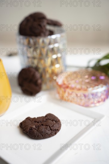 Chocolate chip cookie on white plate, cookie jar in background