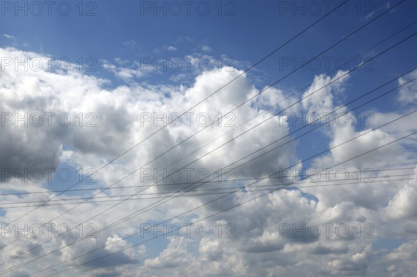 Intersecting high-voltage lines cut through a blue sky with white clouds, Upper Bavaria, Bavaria, Germany