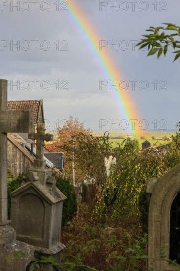 Rainbow over the heritage-protected cemetery near St. Marien Church, Lüdersen mountain village, city of Springe, Hanover region, Lower Saxony, Germany