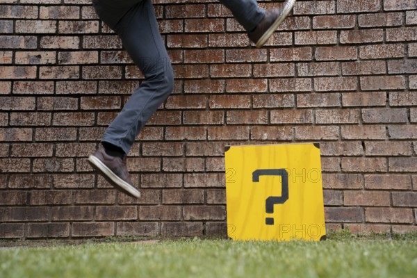 Legs jumping over a box with question mark, symbol