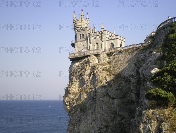 A stunning panorama of the Swallow's Nest castle, towering over the Black Sea. View from the staircase of the 40-meter-high Aurora Rock. The palace itself is a unique historical monument of Crimean architecture and cultural heritage, a well-known landmark for tourists and travelers. It was built between 1889 and 1912. Its owners were wealthy Russian nobles, some of the most influential people in the Russian Empire. Southern Coast of Crimea, Gaspra, Ukraine