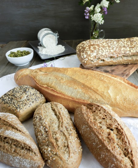 Various freshly baked artisanal breads and rolls presented on a white cloth on a rustic wooden table