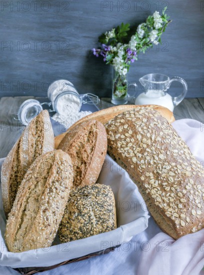 Freshly baked artisanal bread assortment displaying sourdough, multigrain, and seeded loaves and baguettes in a rustic setting