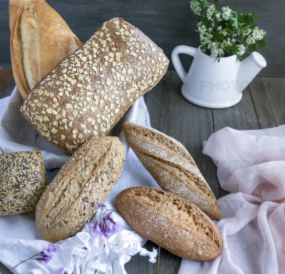 Artisanal bread loaves and rolls featuring various grains and seeds arranged on a white cloth, ready for breakfast