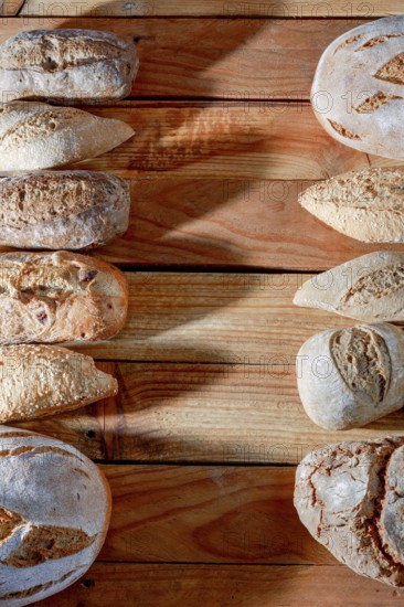 Various types of fresh artisanal bread, including baguettes and round loaves, arranged on a rustic wooden table