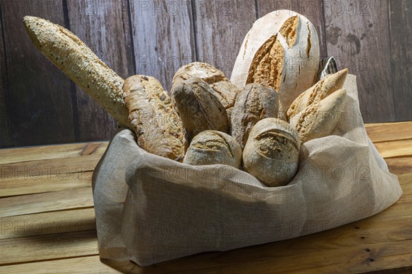 Freshly baked artisanal bread assortment including baguettes and rolls, creating a rustic still life on wood