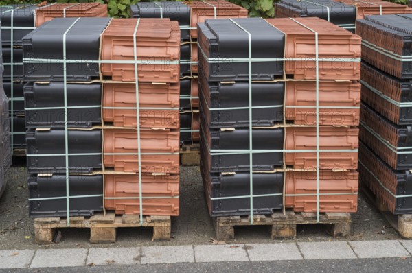 Borken, NRW, Germany, New terracotta and black roof tiles packaged on wooden pallets for construction