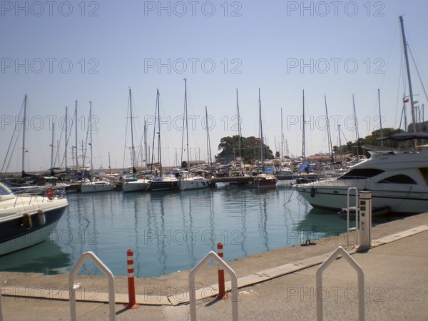 A berth of luxury yachts and boats moored at the local yacht club's pier against the backdrop of the azure and turquoise waters of the Mediterranean Sea, ready for cruising. It's a popular attraction and location for travelers and beach lovers enjoying their vacations on the Turkish Riviera. Antalya Province, Kemer, Türkiye