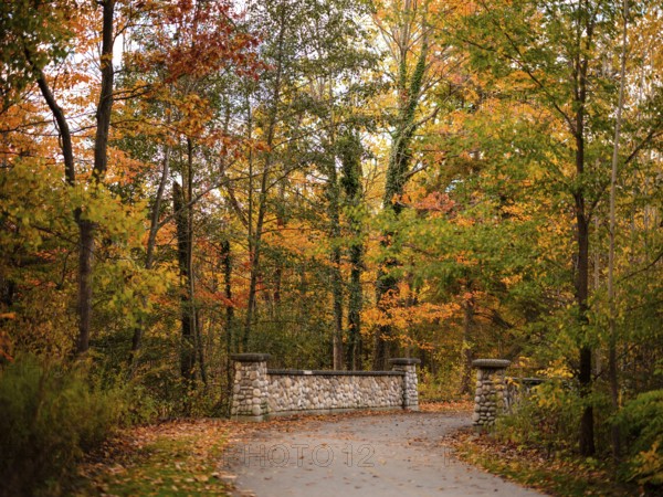 Pathway leading to a stone bridge with trees in autumn colors along the Thames Valley Parkway in London, Ontario, Canada