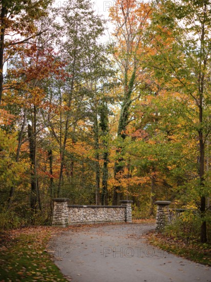 Stone bridge on a path surrounded by trees in brilliant autumn hues along the Thames Valley Parkway in London, Ontario, Canada