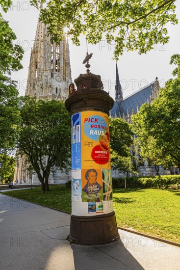 Advertising column, in the back the church towers of the Votive Church, Vienna, Austria