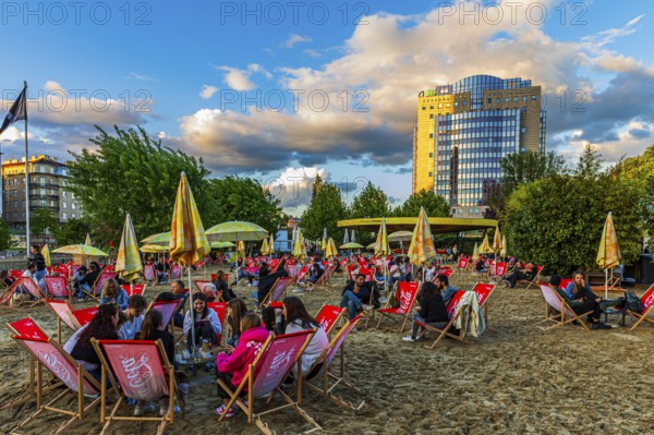 Guests enjoy the evening sun at Strandbar Herrmann, near the Urania Observatory, Vienna, Austria