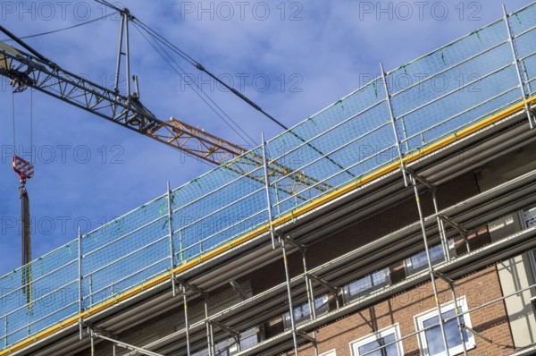 Borken, NRW, Germany, RBuilding undergoing renovation with metal scaffolding and safety netting under a construction crane