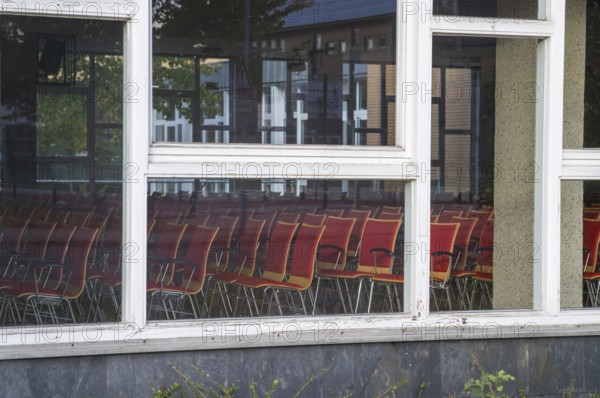 Borken, NRW, Germany, REmpty red chairs filling an auditorium, visible through window panes reflecting the outside