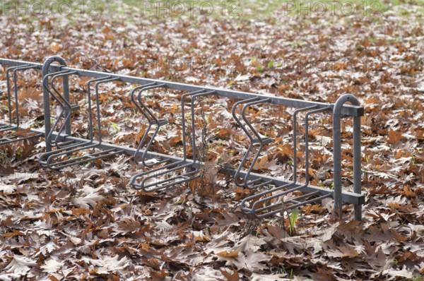 Borken, NRW, Germany, REmpty metal bike rack standing in a park surrounded by dry brown autumn leaves during fall season