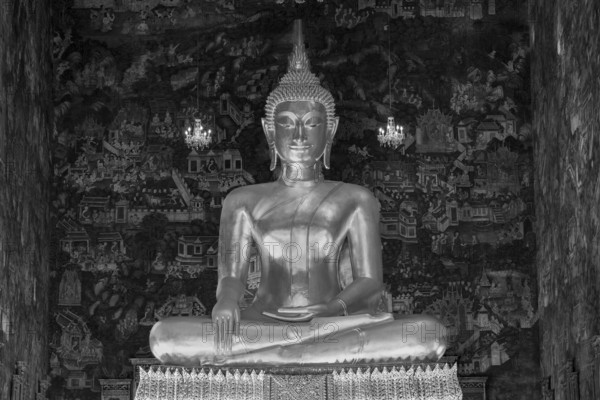 Golden Buddha statue, Phra Buddha Trilokachet surrounded by crystal chandeliers and exquisite wall paintings, interior view of Phra Ubosot or ordination hall, Wat Suthat Thepwararam, Royal Temple, Phra Nakhon, Bangkok, Thailand