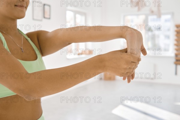 A person is performing an arm stretch in a bright indoor space, promoting flexibility and relaxation. Sunlight fills the room, creating a calm atmosphere for physical activity and well-being