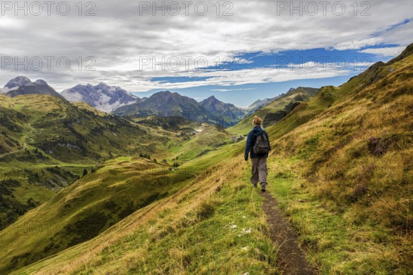 A hiker on a narrow path in the middle of a picturesque mountain landscape, Schröcken, Austria
